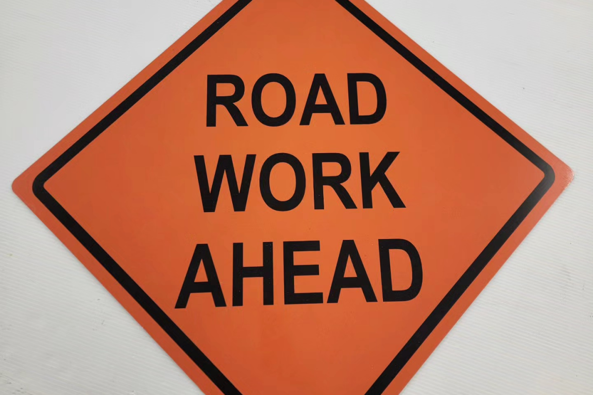 Orange road sign with 'Road Work Ahead' text.