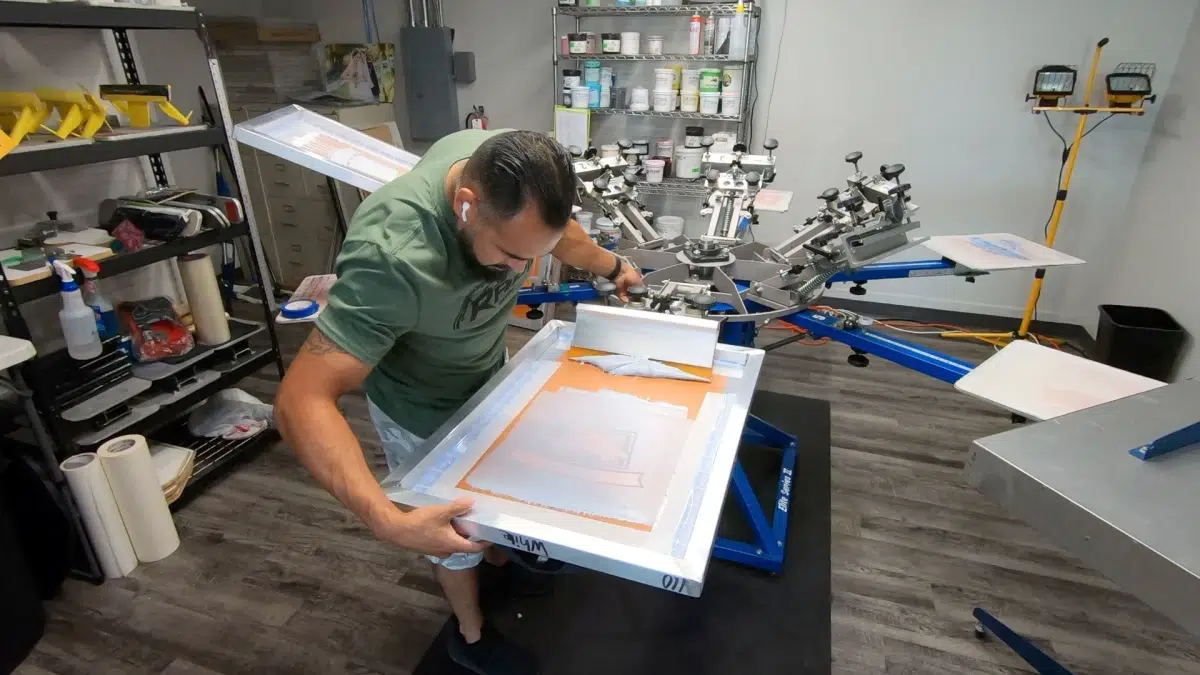 Boost Your Holiday Sales with These Screen Printing Ideas 3 Man working on screen printing equipment.